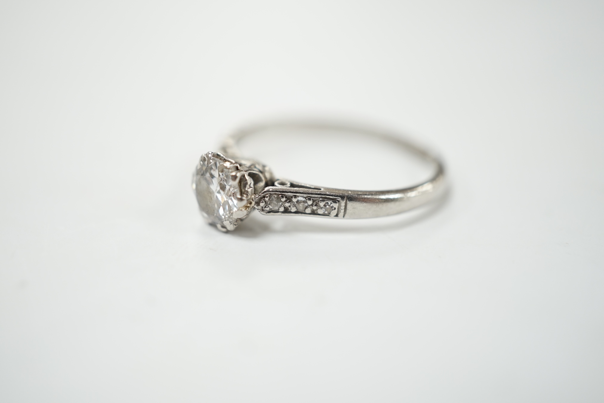 An early to mid 20th century white metal (stamped platinum) and single stone diamond set ring, with six stone diamond chip set shoulders, the stone diameter 5.5mm, depth 3mm, size N, gross weight 2.7 grams. Condition - f
